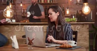 漂亮，深褐色头发的女人在电脑上工作时接电话